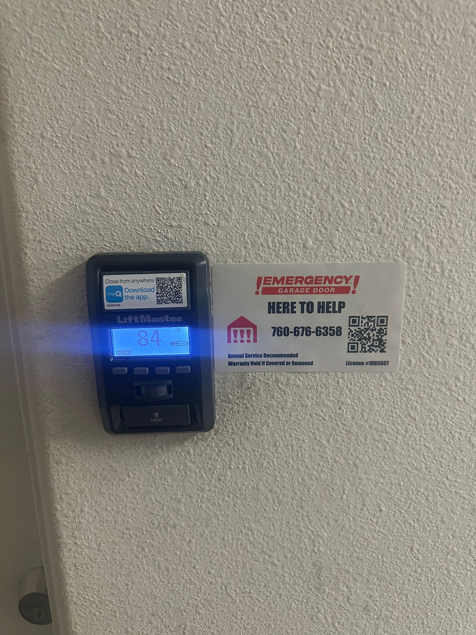 A remote control is sitting on a wall next to a sign.