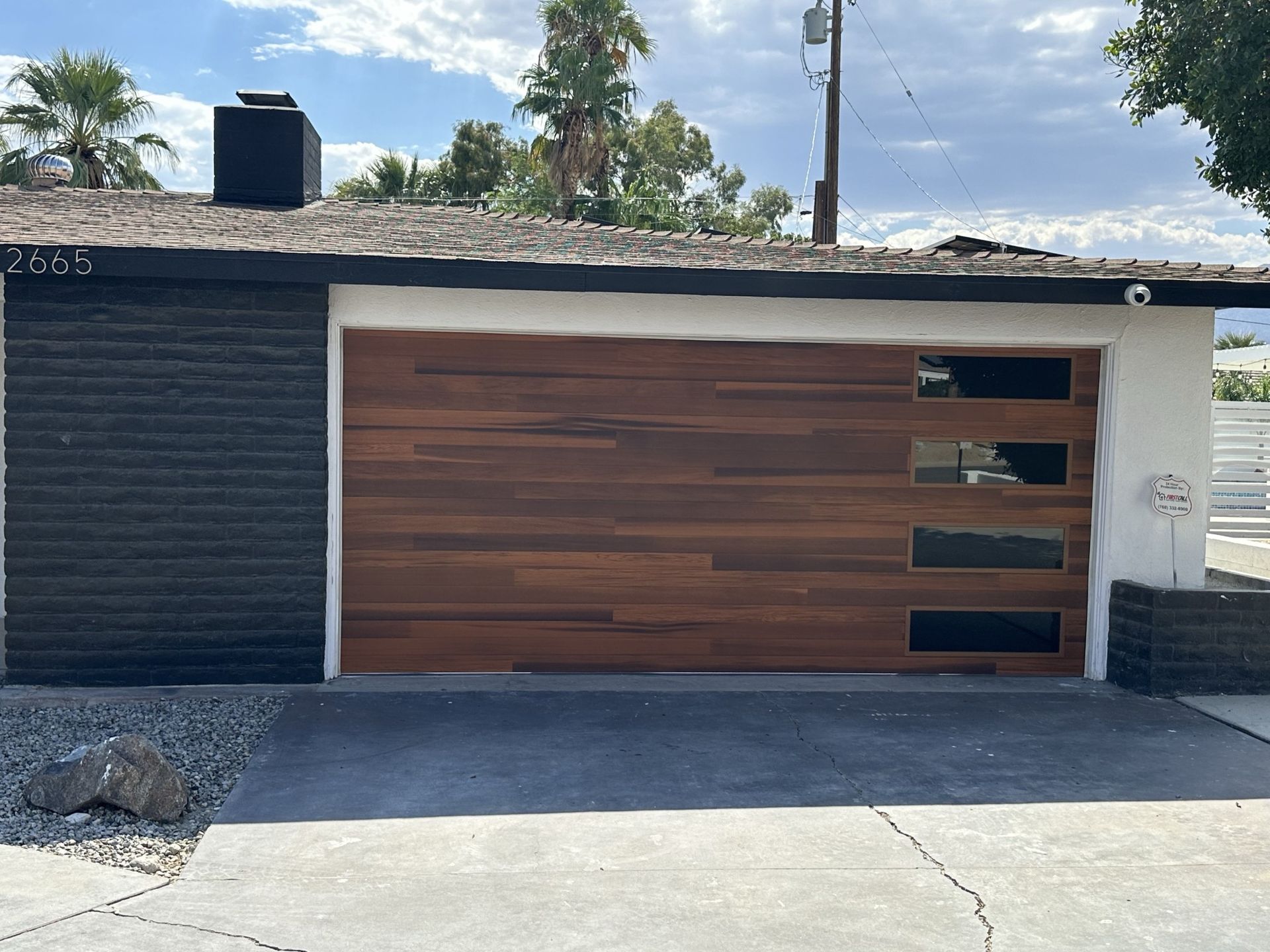 A house with a wooden garage door and a black brick wall