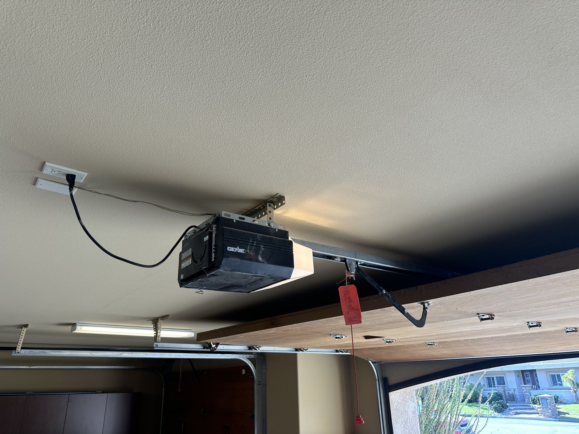 A garage door opener is hanging from the ceiling of a garage.