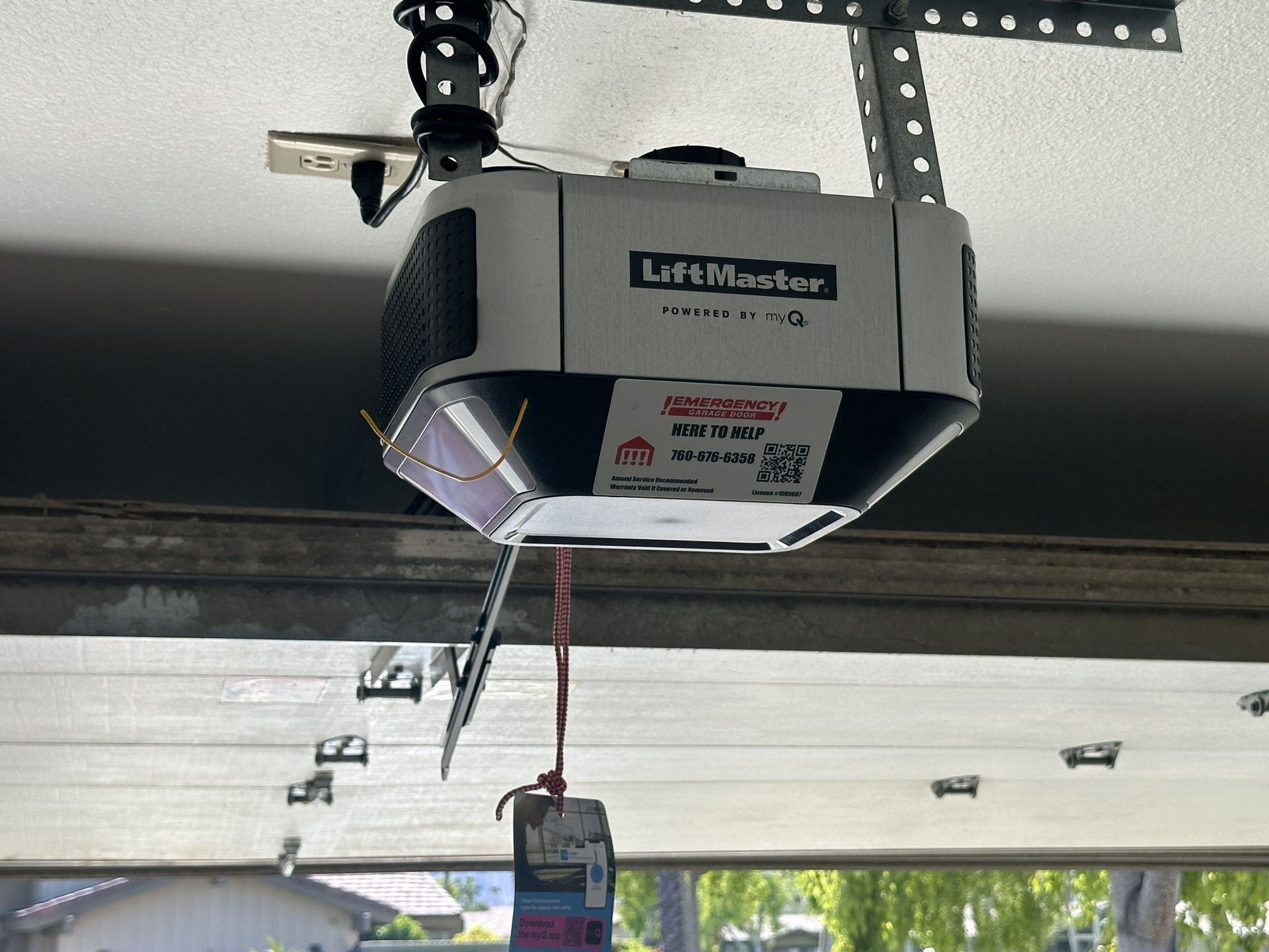 A garage door opener is hanging from the ceiling of a garage.