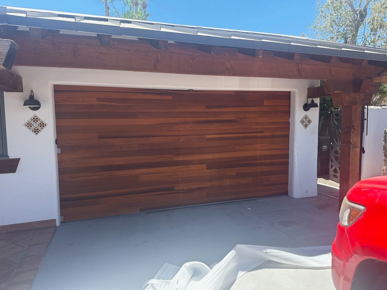 A red truck is parked in front of a wooden garage door