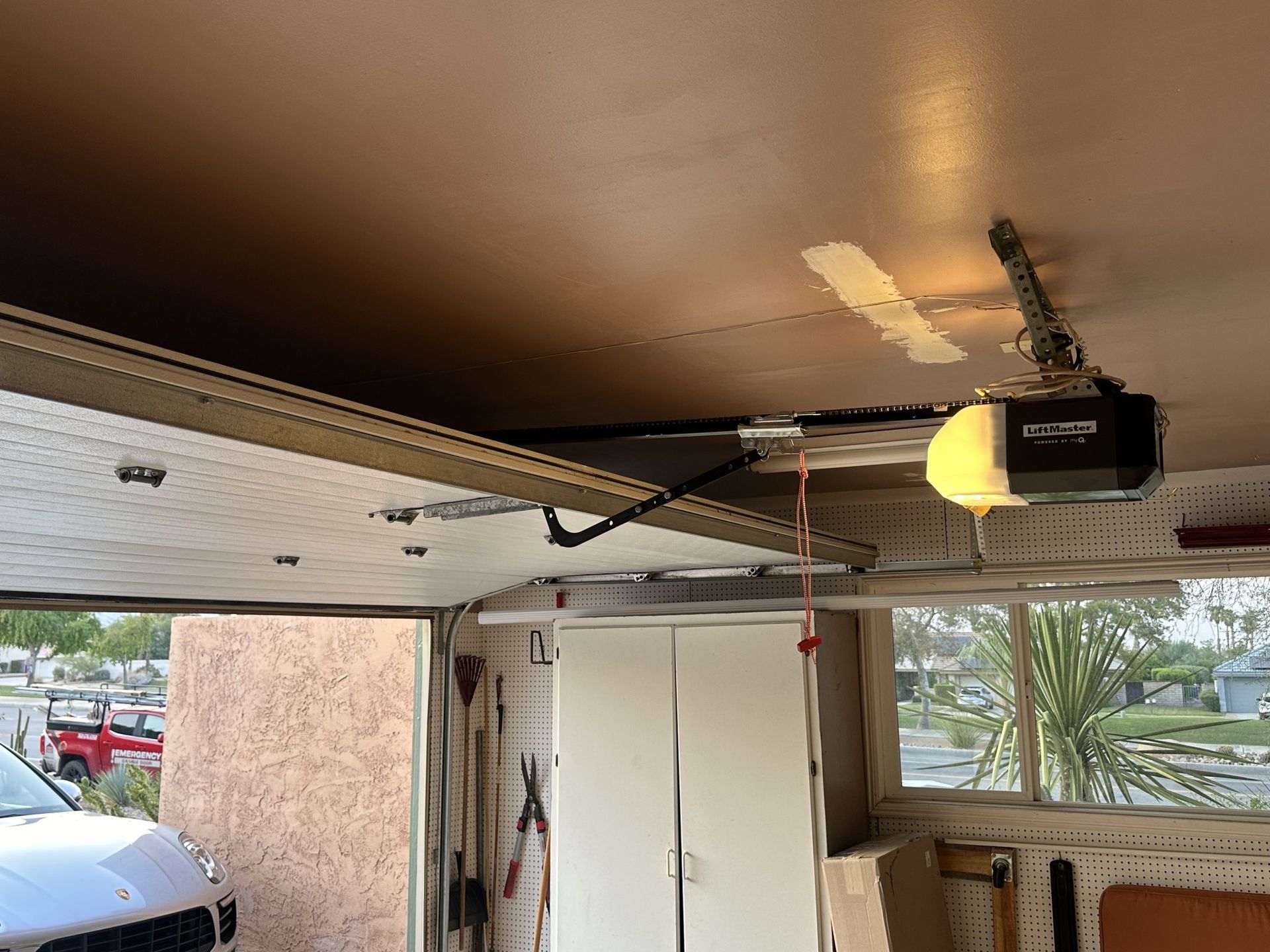 A garage door opener is hanging from the ceiling in a garage.