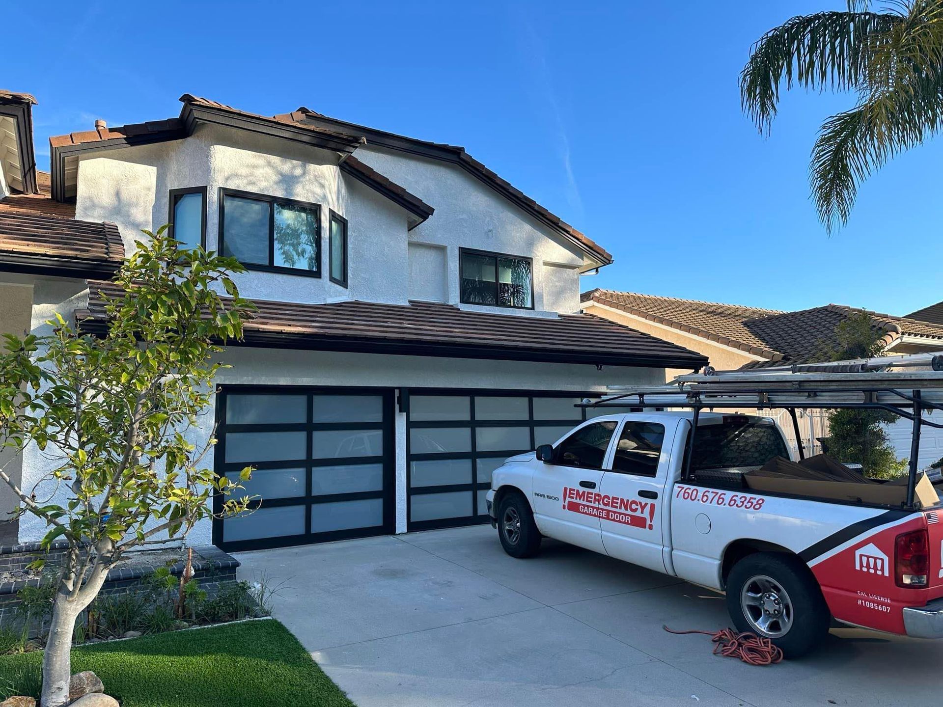 A white truck is parked in front of a white house.