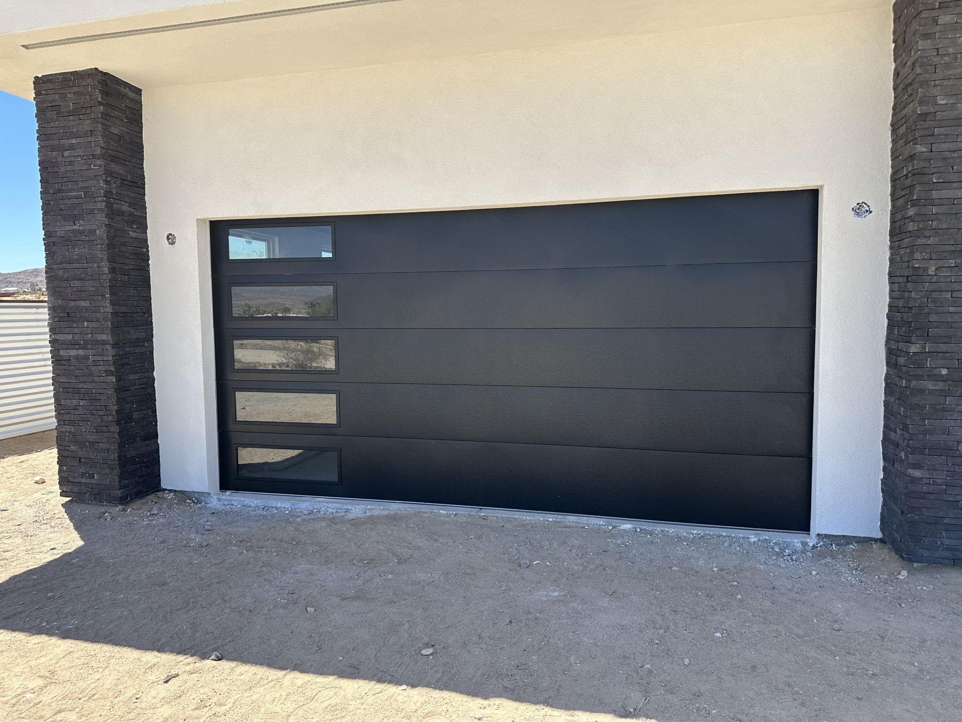 A black garage door is sitting in front of a white building.
