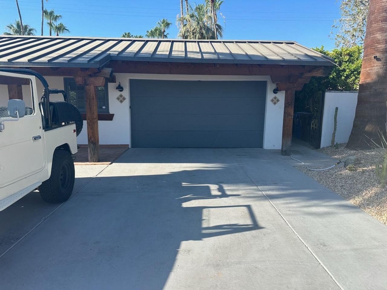 A white jeep is parked in front of a garage door