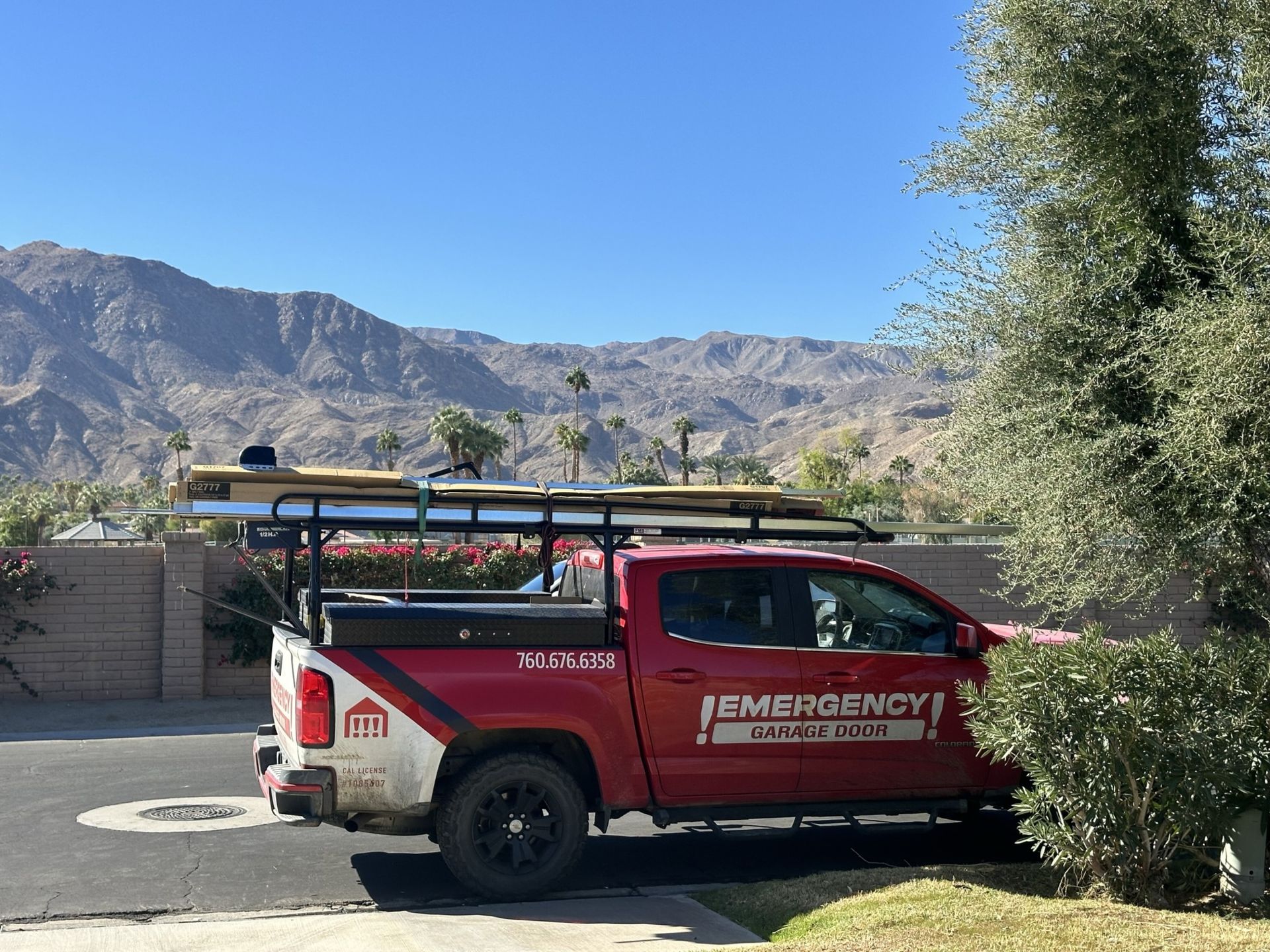 A red emergency truck is parked in front of a house with mountains in the background.