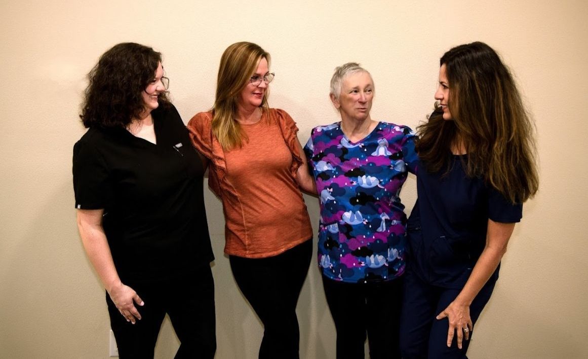 A group of women are standing next to each other in front of a wall.