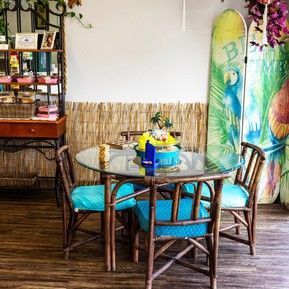 A dining room with a table and chairs and surfboards on the wall.