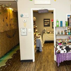 A room with tables and shelves in it and a doorway leading to another room.