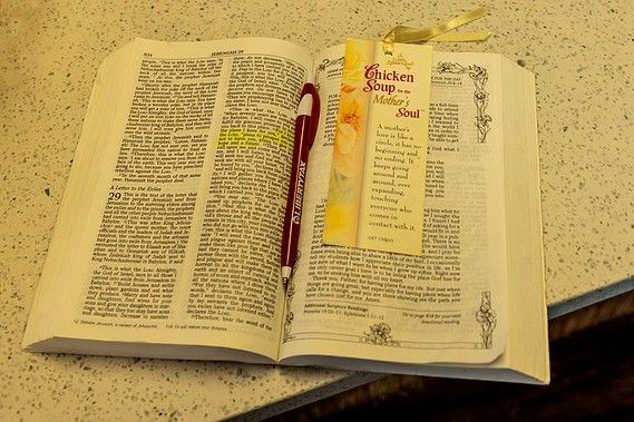 An open bible with a pen and a bookmark on it
