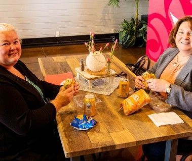 Two women are sitting at a table eating food.