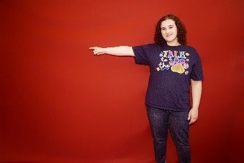 A woman in a blue t-shirt is pointing to the side.