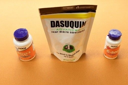 A bag of dasuquin advanced joint health supplement next to two bottles of vitamins.