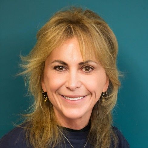 A woman with long blonde hair and earrings is smiling for the camera.