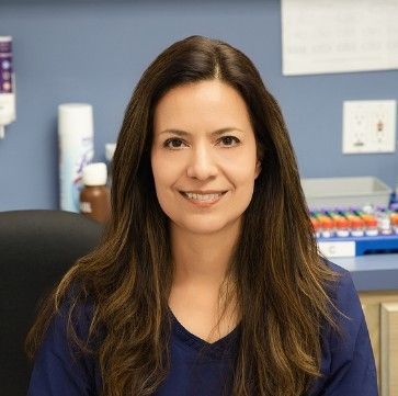 A woman in a blue shirt is sitting in a chair and smiling.