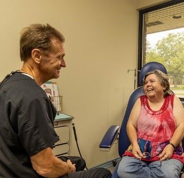 A doctor is talking to a patient who is sitting in a chair.