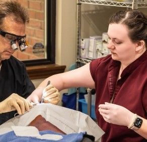 A man and a woman are operating on a patient.