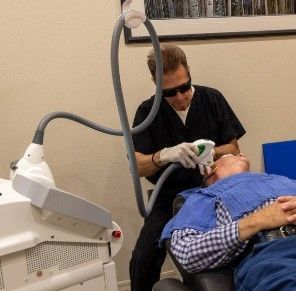 A man is getting a laser treatment on his face.