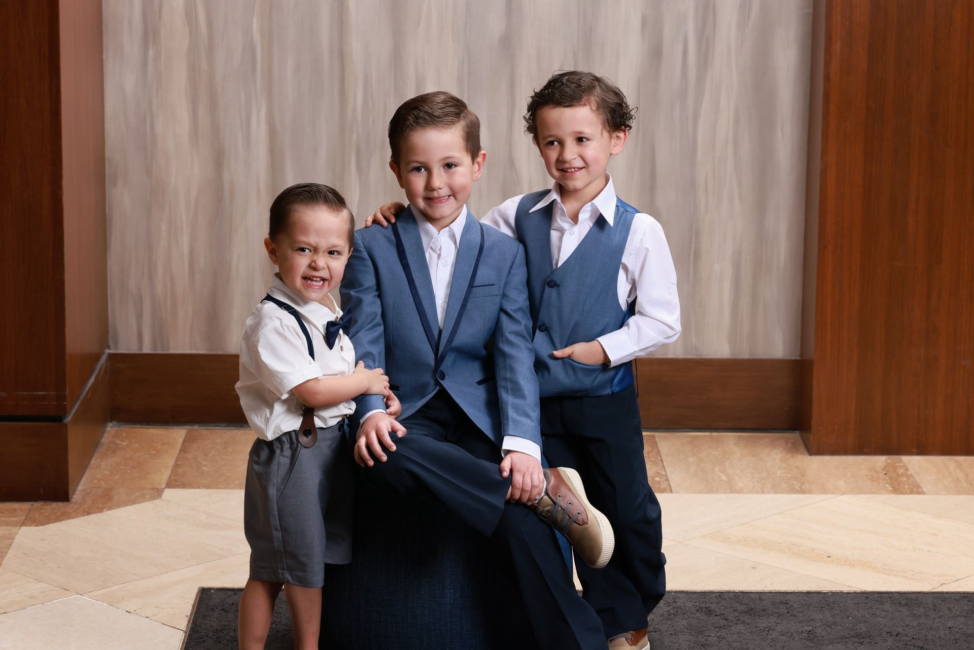 Three young boys in suits are posing for a picture.