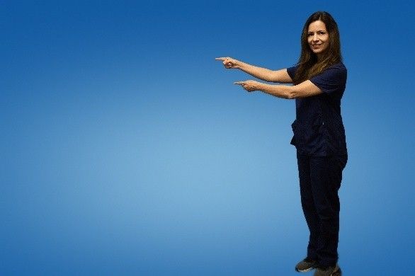A woman in a blue scrub is pointing at something