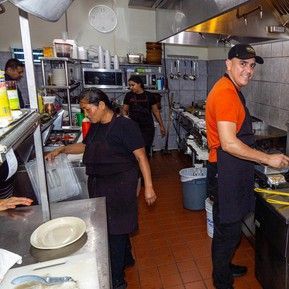 A group of people are standing in a kitchen preparing food.