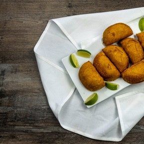 A white plate topped with fried food and lime wedges on a napkin on a wooden table.