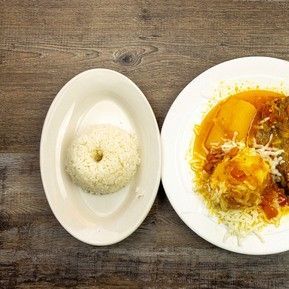 A plate of food with rice and a donut on a wooden table.