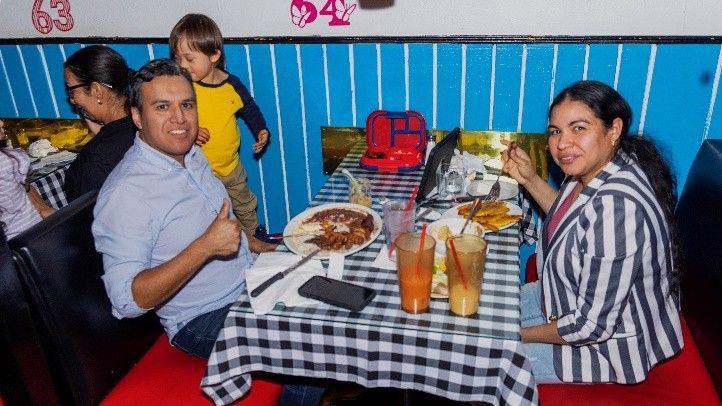 A group of people are sitting at a table in a restaurant eating food.