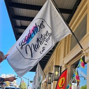 A person is pointing at a flag that says `` good vibes nutrition ''.