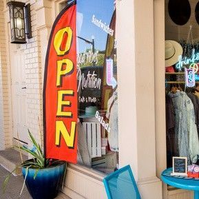 A red and yellow open flag is hanging in front of a store window.
