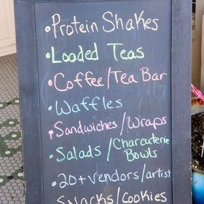 A chalkboard sign that says protein shakes loaded teas coffee tea bar waffles sandwiches wraps salads bowls