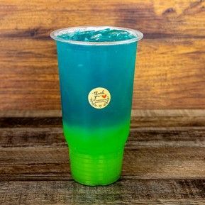 A blue and green drink in a plastic cup on a wooden table.