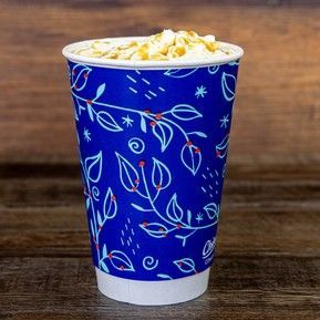 A cup of hot chocolate with whipped cream on top is sitting on a wooden table.