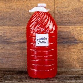 A gallon of red liquid is sitting on a wooden table.