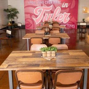 A restaurant with tables and chairs in front of a pink wall.