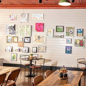 A restaurant with tables and chairs and a wall filled with pictures.