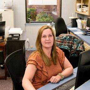 A woman is sitting at a desk in front of a computer