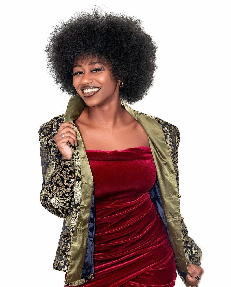A woman with an afro is wearing a red dress and a jacket