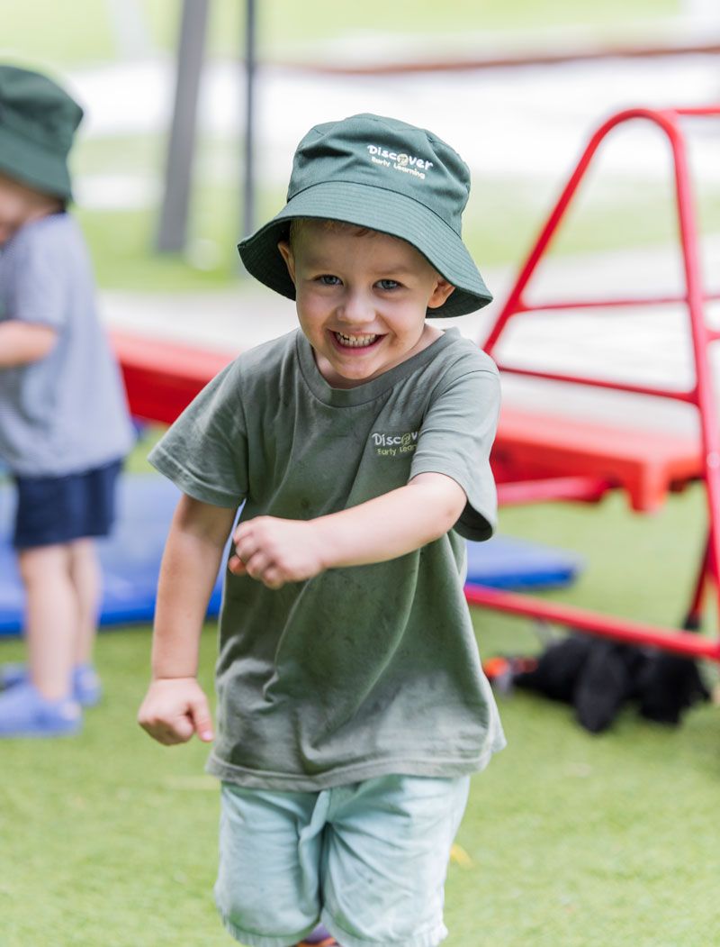 A young boy wearing a green hat and a green shirt at Discover Early Learning.