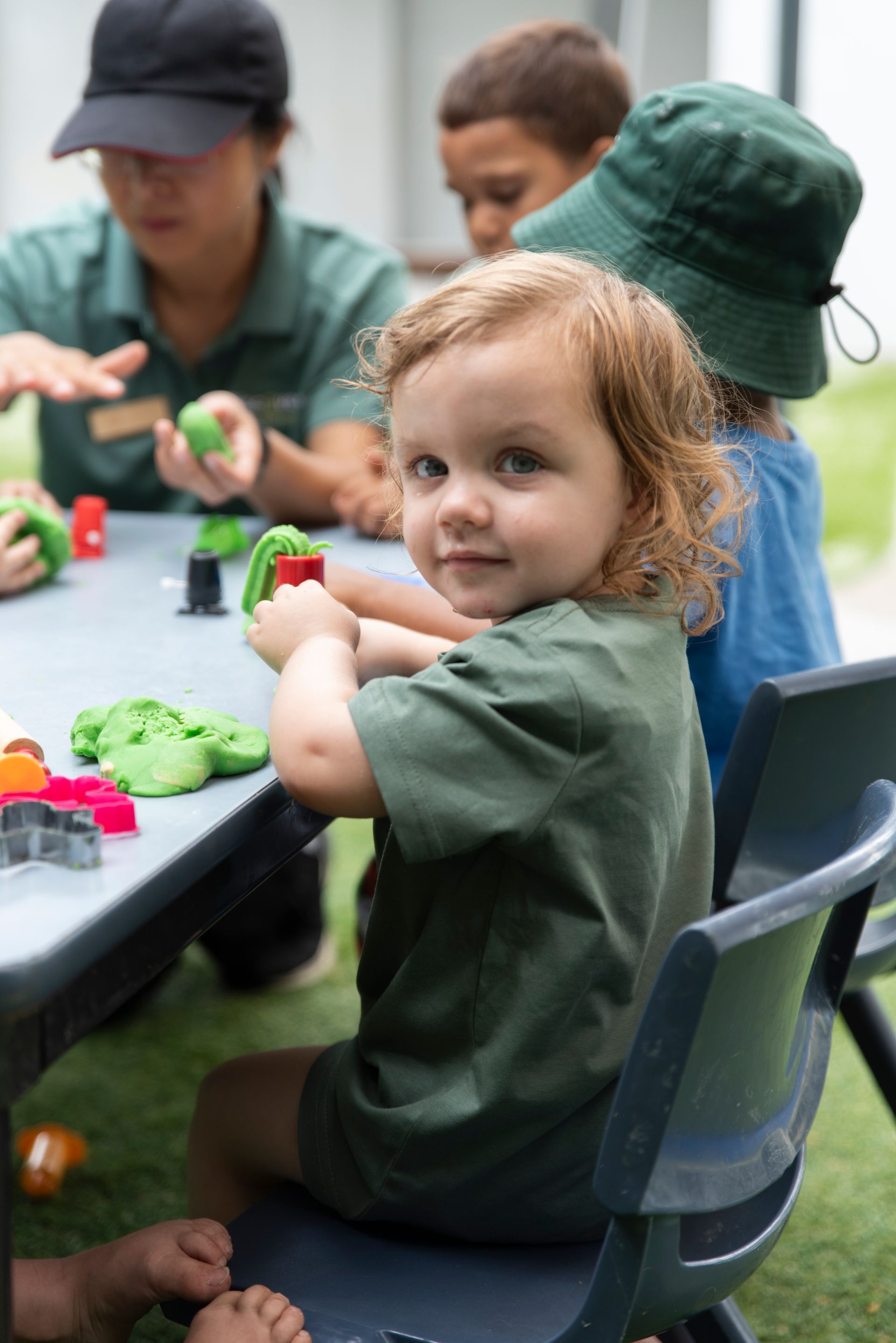 A little girl is sitting at a table playing with play dough  at Discover Early Learning.