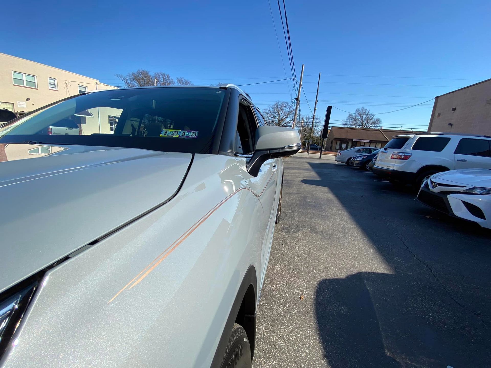 A white car is parked in a parking lot next to a building.