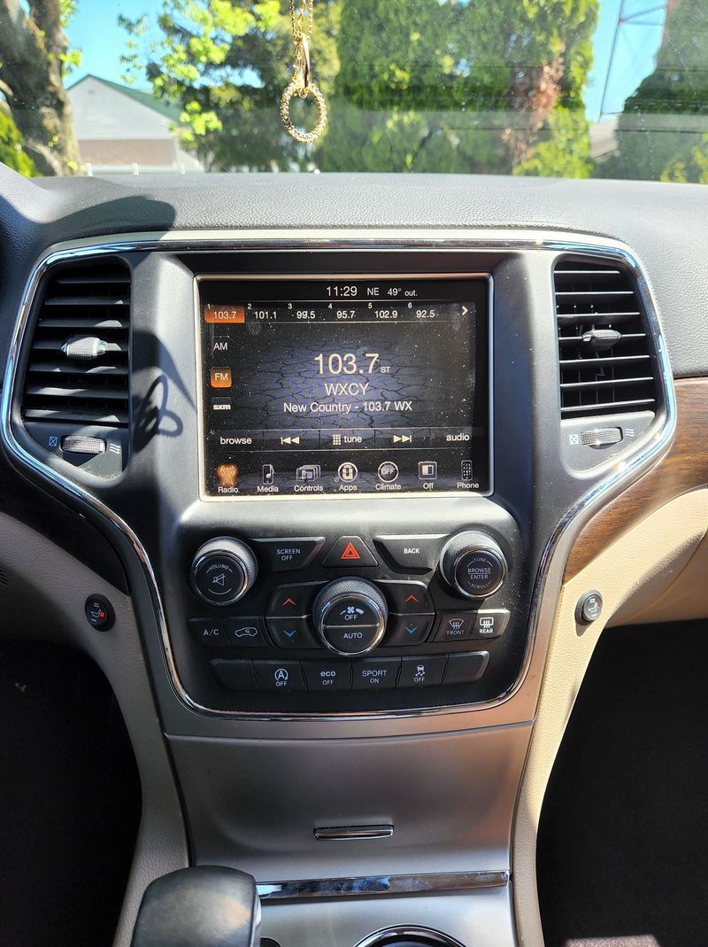 The dashboard of a jeep grand cherokee with a radio on it.