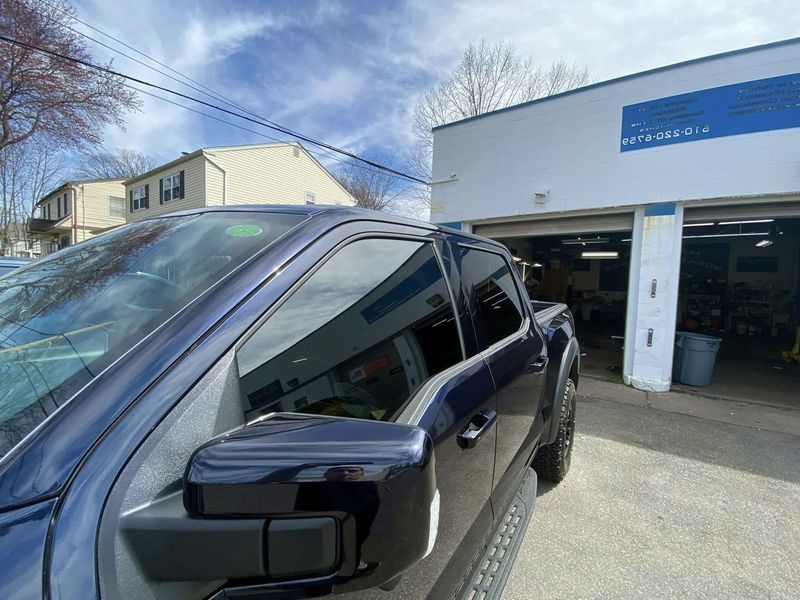 A blue truck is parked in front of a garage.