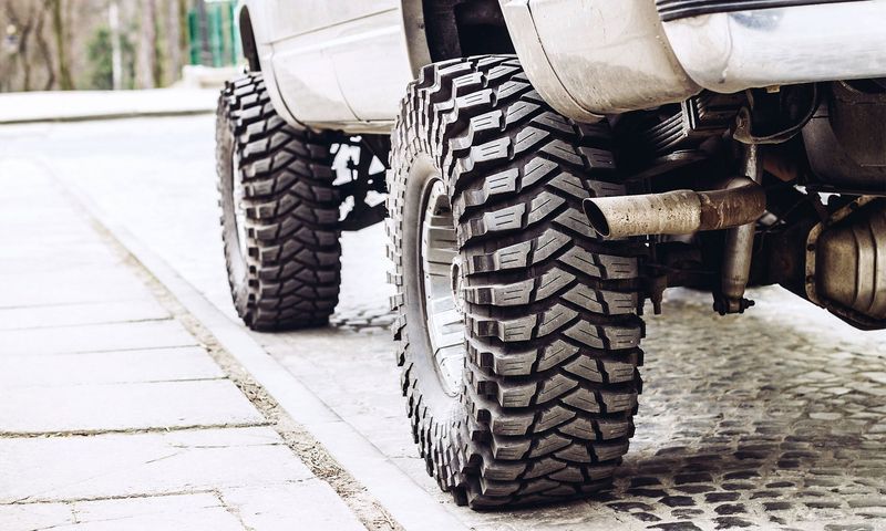 A close up of a truck 's tires on a sidewalk.