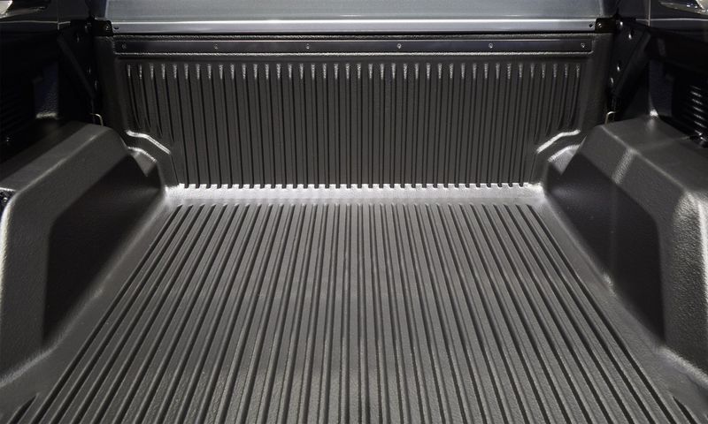 The back of a truck with a rubber mat in it.
