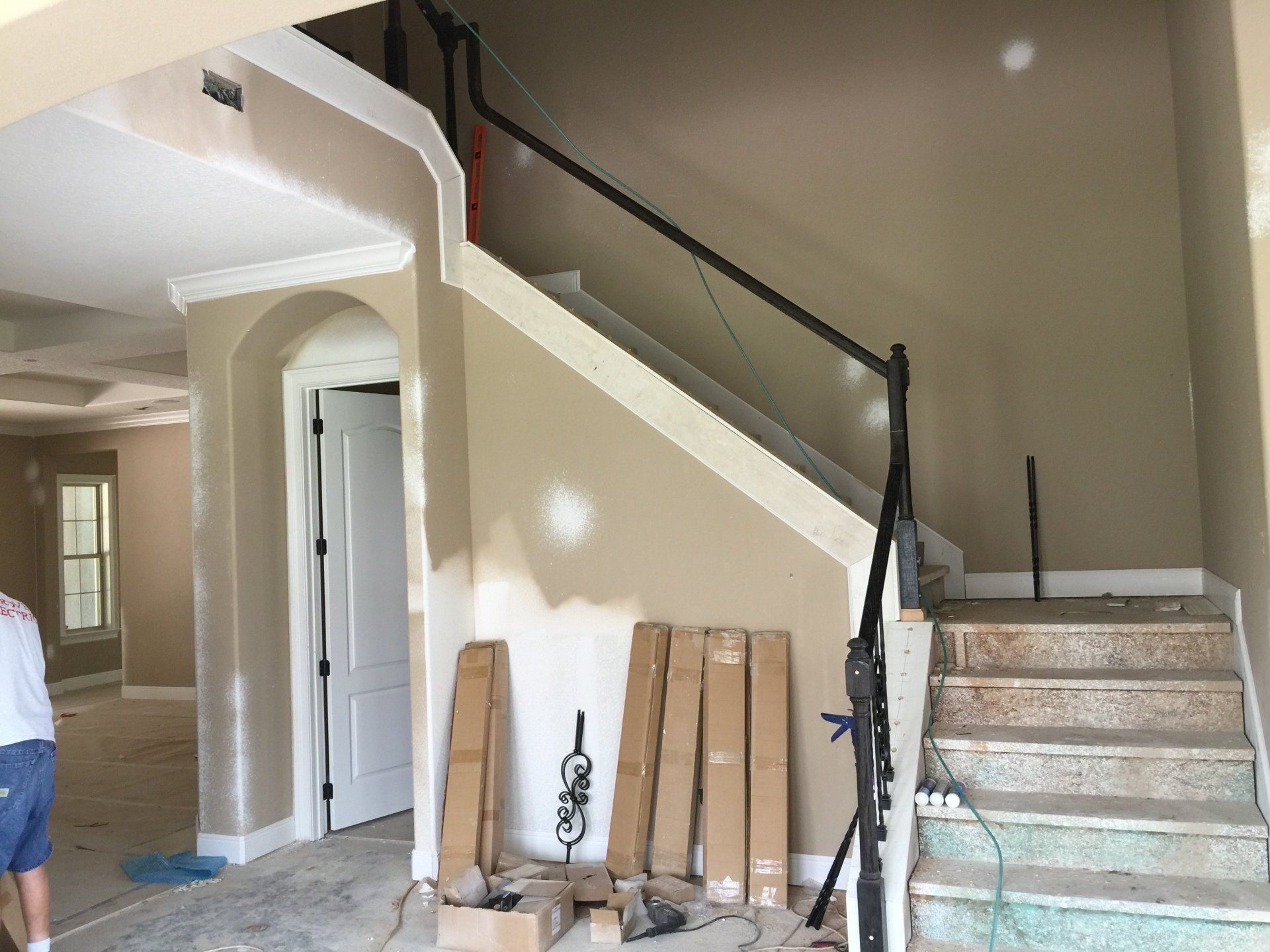 Interior view of a stairwell under construction with unfinished walls, stairs, and a temporary handrail.