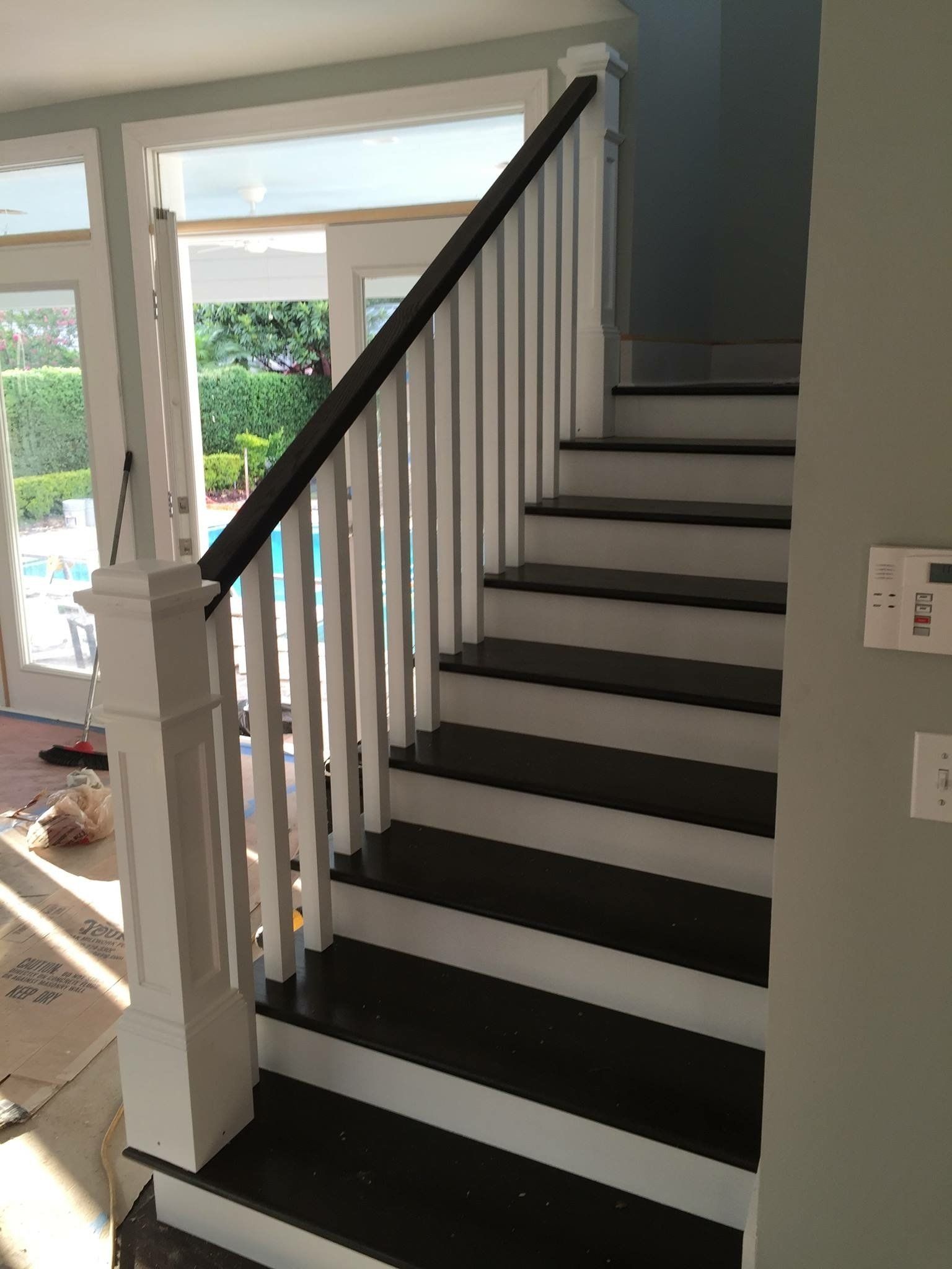 Staircase with black treads, white risers and balusters, and a dark handrail.