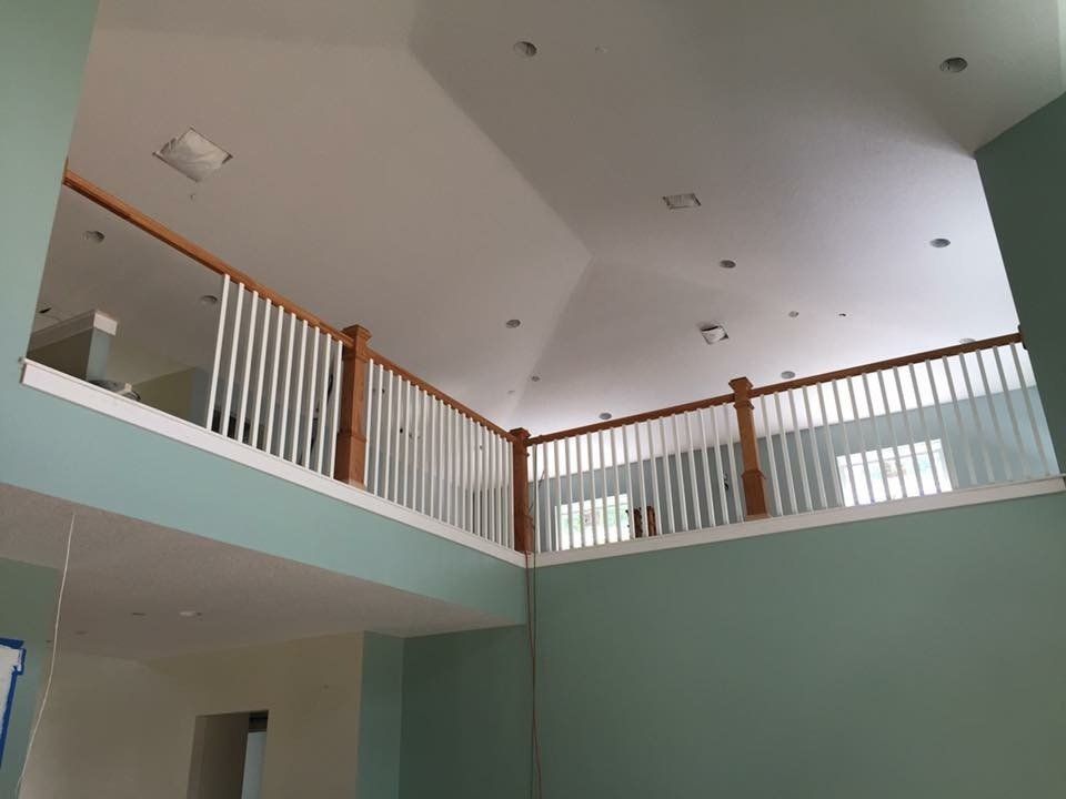 Interior view of a two-story room with a balcony.  Light blue walls, white railing and ceiling.