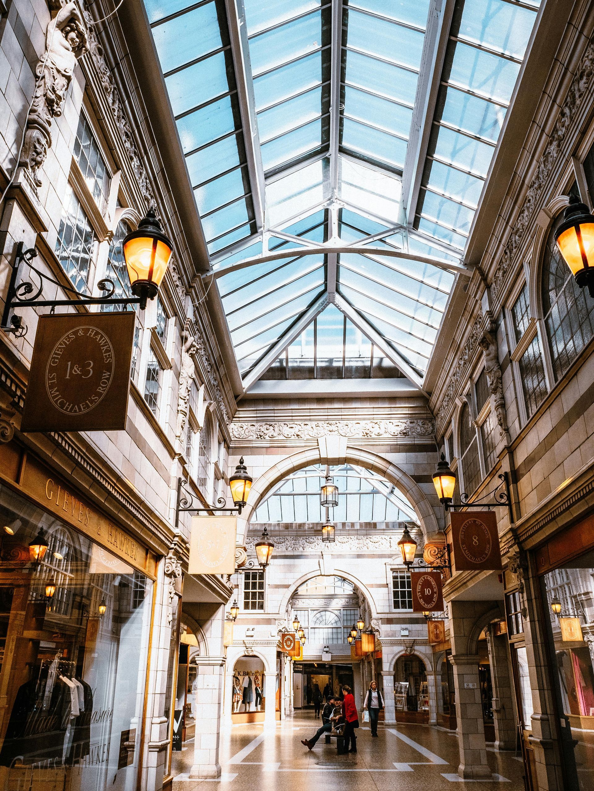 People walking toward Oviedo Mall entrance, sign in foreground, trees, and buildings visible.