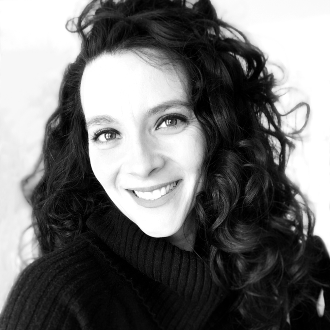 black and white photo of a woman with curly hair smiling and wearing a black turtle neck